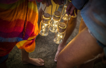 Hipster friends having fun together at beach camping party - Friendship travel concept with young people holding neon led lanterns at summer sea camp - High iso image with night dark vignetting filter