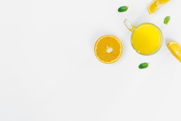Cut orange, slices, mint leaves, orange juice in a glass top view on a white background, flat lay. The concept of healthy, proper nutrition, ditox.