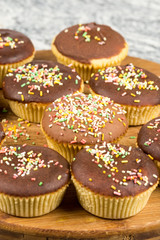 Vanilla cupcakes with chocolate cream and colorful sprinkles