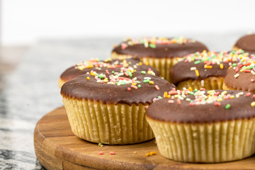 Vanilla cupcakes with chocolate cream and colorful sprinkles
