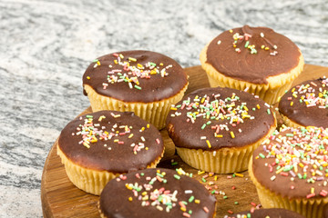 Vanilla cupcakes with chocolate cream and colorful sprinkles