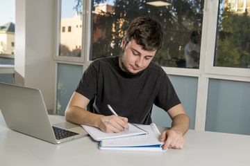 young student teenager studying with computer laptop writing on notepad happy and confident preparing exam at library classroom desk
