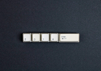 2018 enter on computer keys button. Flat lay view from above on the table with computer keyboard keys buttons on a dark background. New year 2018 card.