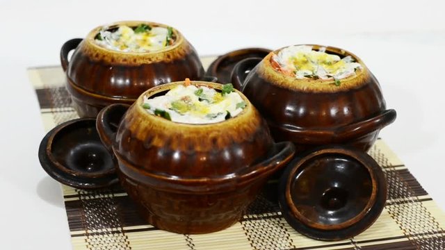 Clay pots with meat dish before baking rotate