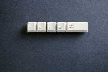 Computer keyboard keys with 2018 enter written using the white buttons on a dark background. Holiday technology concept. New year 2018 card.