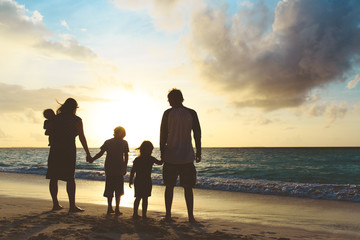 Fototapeta premium happy family with tree kids walk at sunset beach