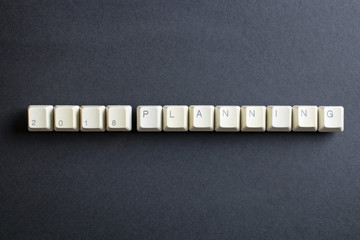 Planning 2018 new year. Flat lay view from above on the table with computer keyboard keys buttons on a dark background.