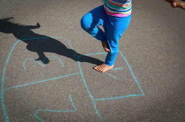 little girl playing hopscotch on playground