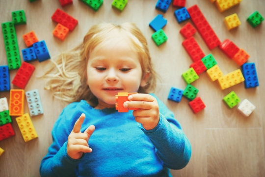 cute little girl play with plastic blocks