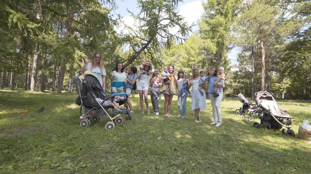 Young mothers with children and strollers in the Park. Look at the camera and waving.
