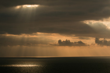 sun through clouds over sea