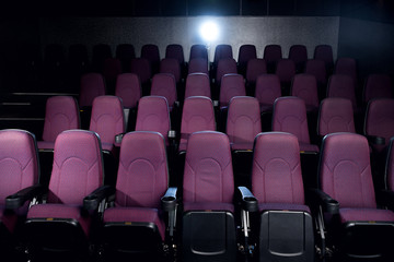 red seats in empty dark movie theater with back light
