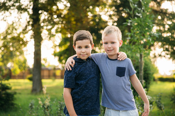 Two children are playing in the park. Two beautiful boys in T-shirts and shorts have fun smiling. They eat ice cream, jump, run. Summer is sunny © Aleksandr