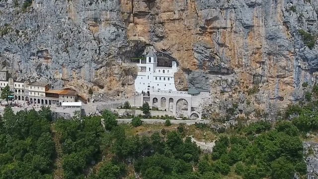 Aerial view on Ostrog Monastery church under tall mountain walls, Montenegro

