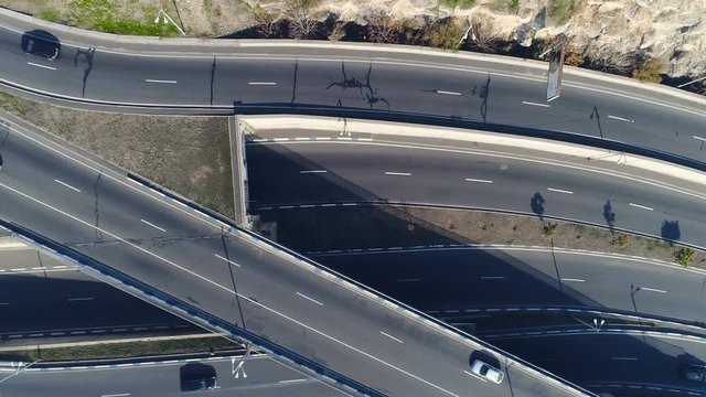 Aerovideo: unmanned aircraft flying over free interstate expressway with machines at summer day. The modern architecture of curvy autoban, many different winding turn. Casual lifestyle in megapolis