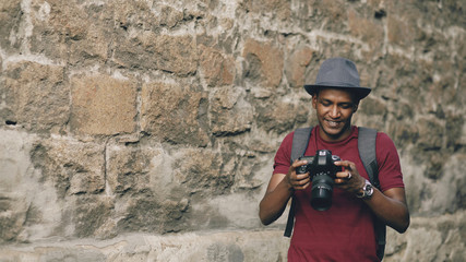 Mixed race happy tourist man taking photo on his dslr camera standing near famous building in Europe