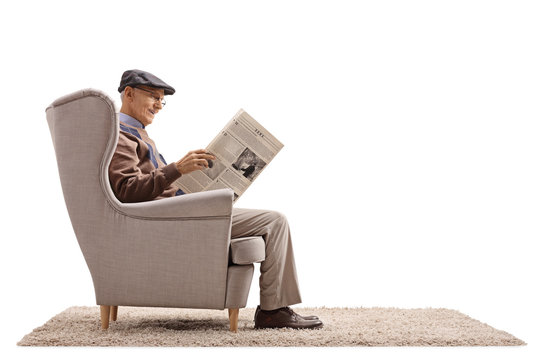 Senior seated in an armchair reading a newspaper