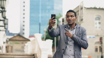 Angry Mixed race businessman having online video chat in business conference using smartphone
