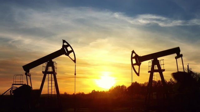 working oil pumps silhouette against sunset, timelapse 4k
