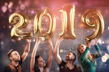 A group of merry young people hold numbers indicating the arrival of a new 2019 year. The party is dedicated to the celebration of the new year. Concepts about youth togetherness lifestyle