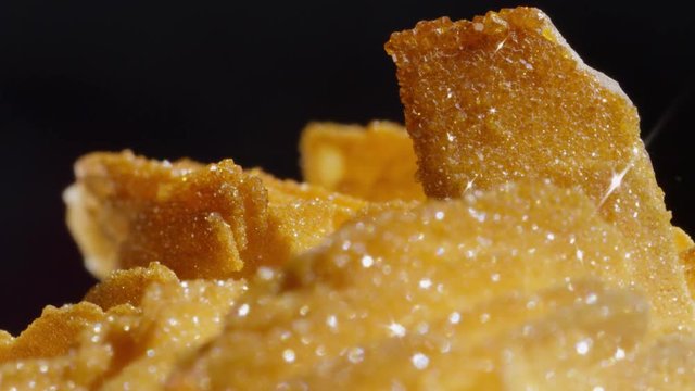 MACRO DOF: Detailed shot of rough surfaced golden barite vanadinite gemstone. Charming brown and gold semi precious stone with coarse surface glittering. Precious golden mineral with glittery details