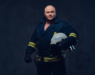 Fototapeta premium Firefighter in uniform over dark grey background.