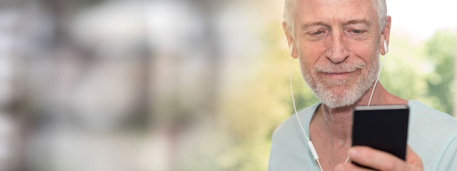 Portrait of mature man listening music with earphones, light effect