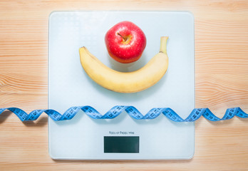 The concept of weight loss, healthy eating. Scales, roulette, apple, banana. View from above