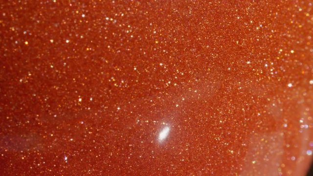 SLOW MOTION CLOSE UP: Captivating decorative precious sunstone beaming in bright sunlight. Sunstone glittering in intense sunrays. Reflective spherical orange stone exuding bright bundles of light.