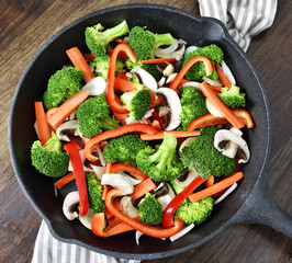 Fresh vegetables in an iron pan. Healthy eating or scene with fresh broccoli, onion, mushrooms,...