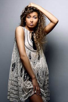Beautiful young girl in a transparent lace dress on a gray background