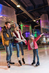 happy young family with one child skating together on rink