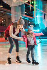 Obraz na płótnie Canvas beautiful happy mother and daughter ice skating together on rink