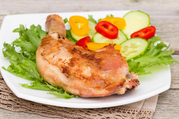 Spicy grilled chicken thigh and vegetables on a white plate.