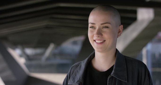 Close portrait of beautiful young woman with buzz cut lauhing into camera
