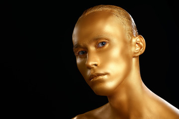The guy painted in gold paint. completely. portrait. beauty on a black background. Shiny Gold foil.