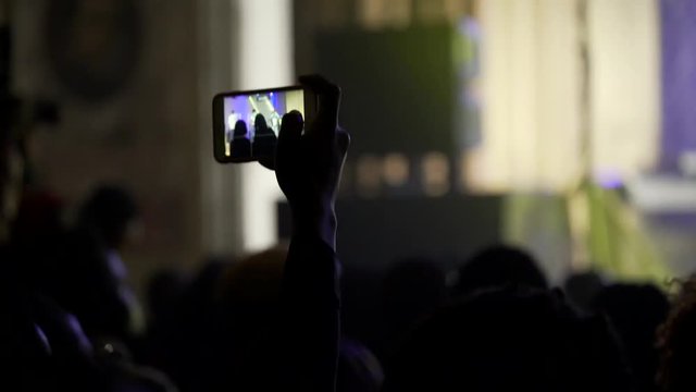 Black Africans pray in the concert hall. Dance and raise hands up. Shooting through your hands in the backlight. Take video to your phone.