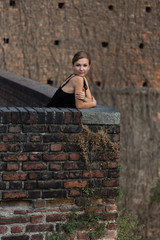 Beautiful girl dressed in black dress standing in castle