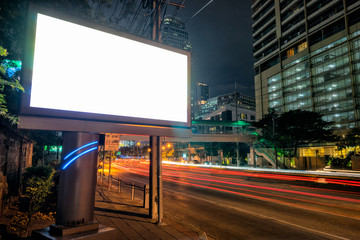 Blank template for outdoor advertising or blank billboard with light trail to business district in twilight.