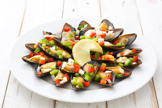 Steamed mussels with peppers and onion on white  wooden table