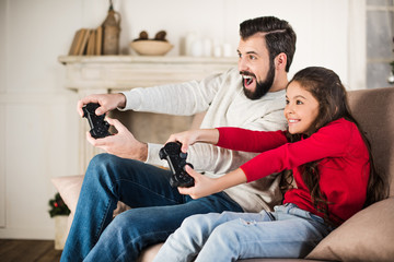 happy father and daughter playing video game at home