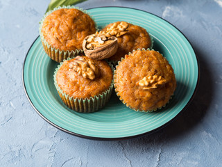 Home made Carrot spiced muffins with walnuts on green dish.