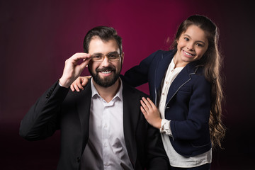 father touching glasses and looking at camera on burgundy