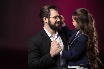 daughter fixing father glasses on burgundy