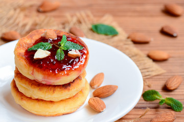 Cottage cheese pancakes with berry jam, almonds nuts and mint on a served plate. Healthy cottage cheese almond flour pancakes. Closeup