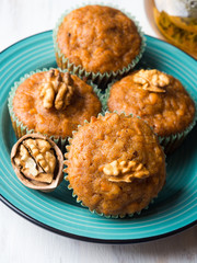 Home made Carrot spiced muffins with walnuts on green dish.