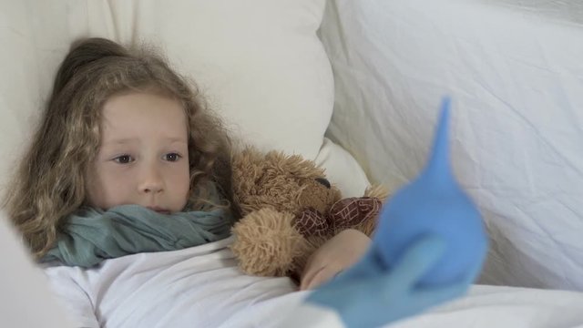 Little frightened girl looking at enema in doctor's hand, illness and healthcare
