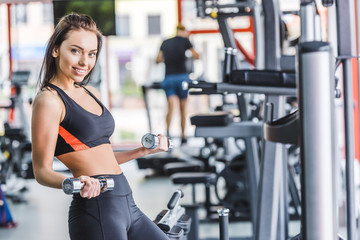 young sportive woman doing exercise with dumbbells at gym
