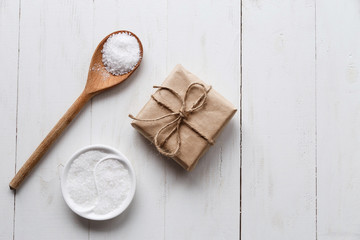 Fototapeta na wymiar Healthy Sea Salt with giftbox on white wooden background. Flat lay. Copy space.
