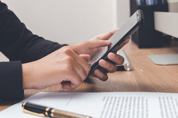 Businesswoman touching screen on mobilephone for check detail with documents before signing terms and conditions, business concept